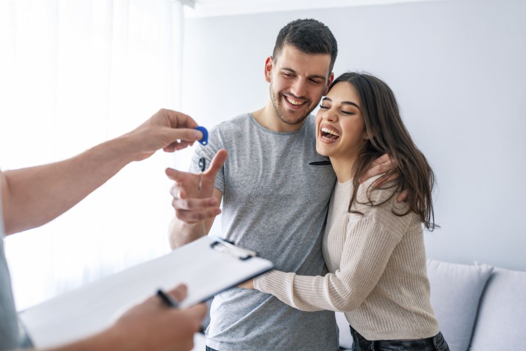 Smiling man and woman taking keys from person off camera