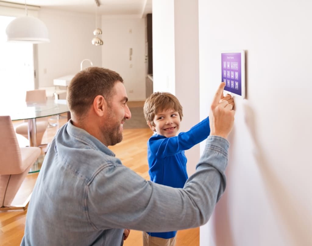 Man and child smile while using touchscreen thermostat