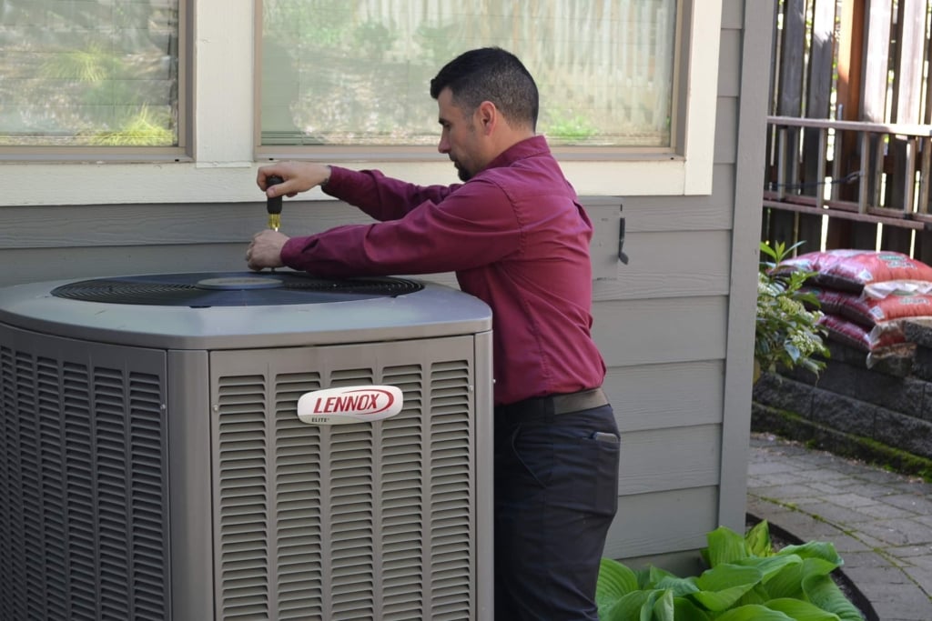 Expert Portland AC maintenance technician performing maintenance on a central AC unit.