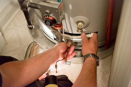 Plumber repairing a water heater in Portland home.