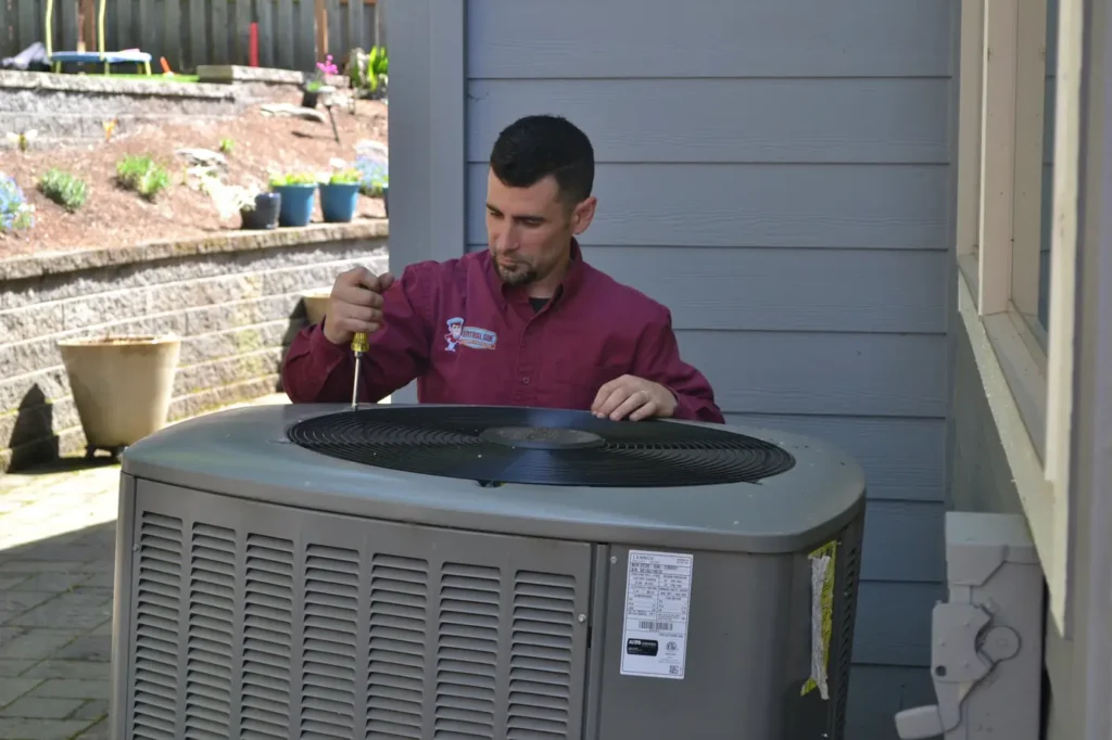 Technician fixing a broken AC compressor in Portland.