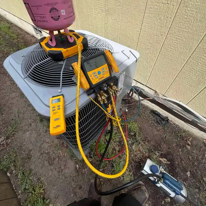 HVAC technician servicing an AC condenser unit in Portland with refrigerant gauges and diagnostic equipment.