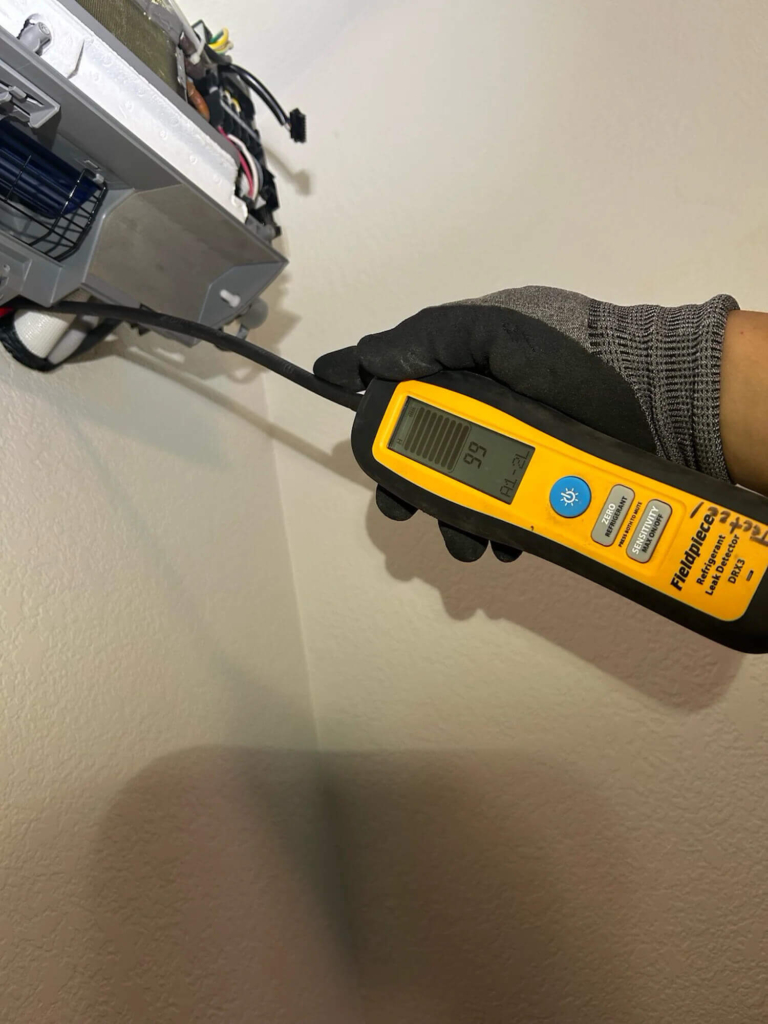 Technician diagnosing why an AC is leaking water inside the house by inspecting the indoor air handler in a Portland home.