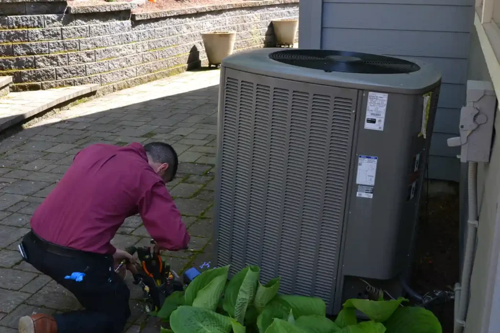 HVAC technician inspecting an outdoor AC condenser unit on a Portland patio for smoke odor and indoor air quality issues.